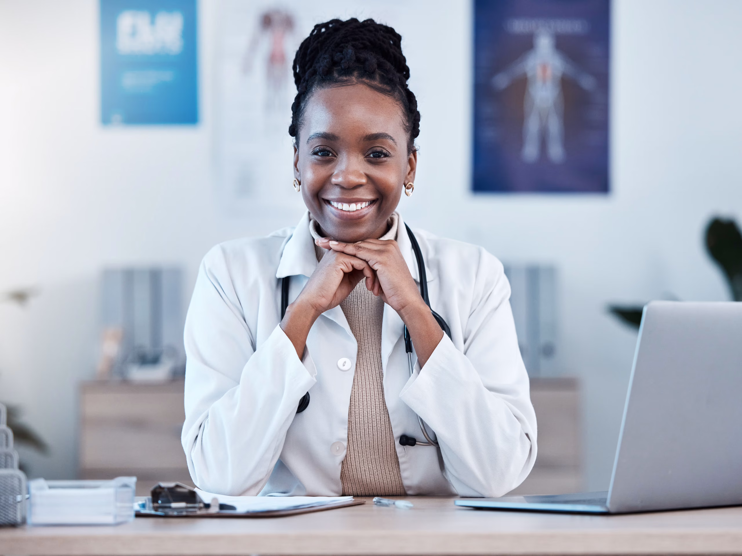 Smiling South African female doctor sitting at desk in a private healthcare clinic